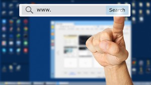 Hand clicking a search button. Computer monitor in the background